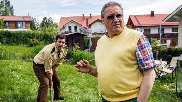 Polizeirat Girwidz (Michael Brandner, rechts) steht in Freizeitkleidung neben Riedl (Paul Sedlmeir) und beobachtet den Fortgang der Gartenarbeit. Dabei gibt er Riedl immer wieder Anweisungen. | Bild: ARD/TMG/Chris Hirschhäuser