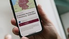 08.12.2022, Berlin: Ein Mitarbeiter des Bundeskanzleramts hält sein Mobiltelefon am Warntag 2022 im Foyer des Kanzleramtes in der Hand, wobei auf dem Display eine Probe-Warnmeldung zu sehen ist. Am 08.12.2022 wurde bundesweit die Infrastruktur zur Warnung der Bevölkerung getestet. Foto: Wolfgang Kumm/dpa +++ dpa-Bildfunk +++ | Bild: dpa-Bildfunk/Wolfgang Kumm