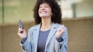 Eine Frau wirkt sehr glücklich, sie hat ein Smartphone in der Hand | Bild: mauritius images / Westend61 / Javier Sánchez Mingorance