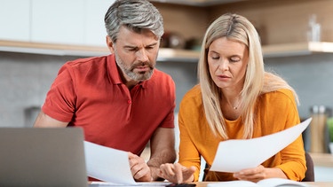 Mittelaltes Paar liest die Post und rechnet etwas nach  | Bild: mauritius images / Prostock-studio / Alamy / Alamy Stock Photos